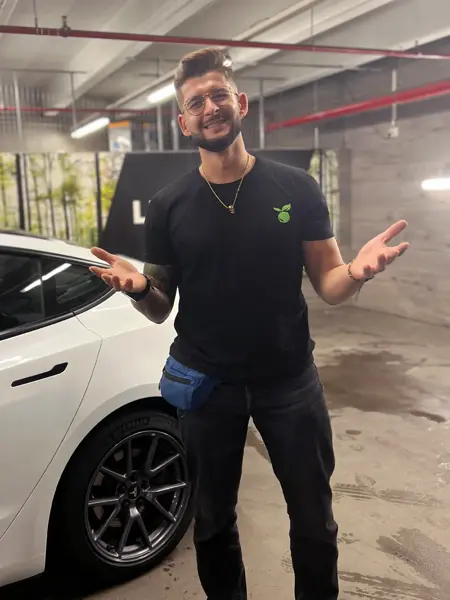 Mann som står og smiler ved en bil