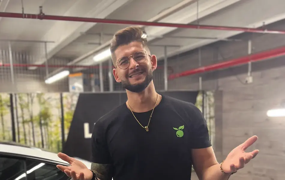 Mann som står og smiler ved en bil