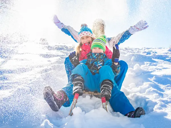 Happy family having fun together on the snowy mountain, on a sled.