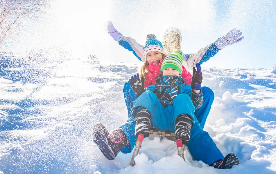 Happy family having fun together on the snowy mountain, on a sled.