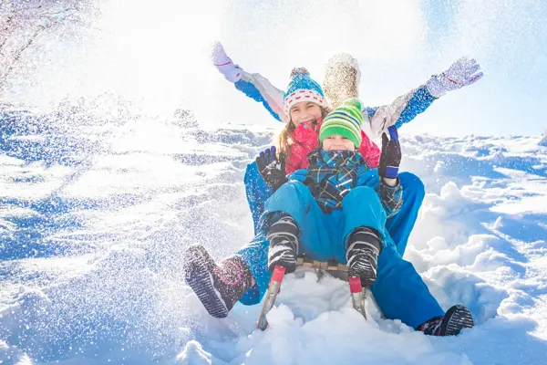Happy family having fun together on the snowy mountain, on a sled.