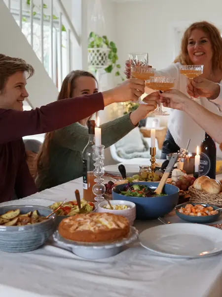 Dekket bord med mat og folk som smiler og deler mat