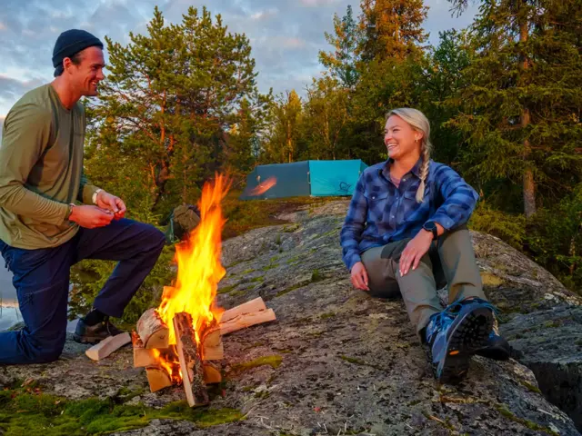 Mann og dame som tenner bål ved ett vann
