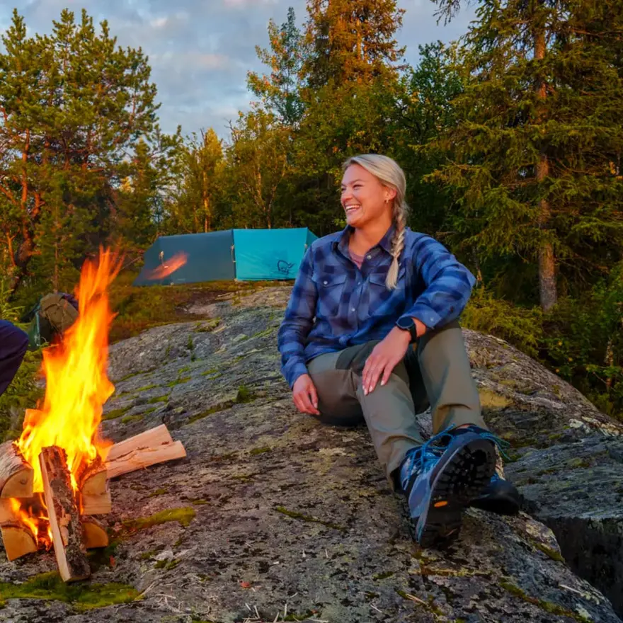 Mann og dame som tenner bål ved ett vann