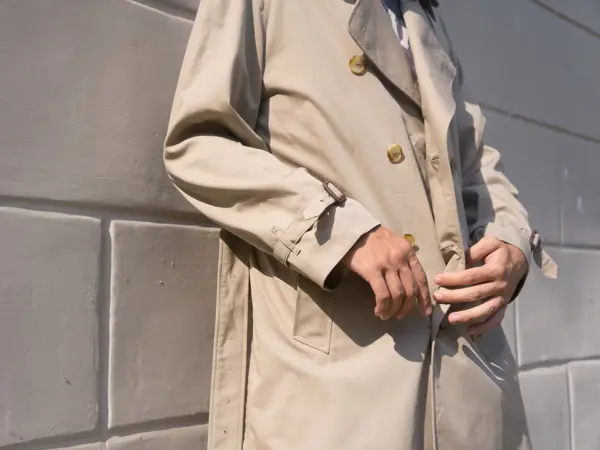 Nærbilde av en beige klassisk trenchcoat på en mann utendørs