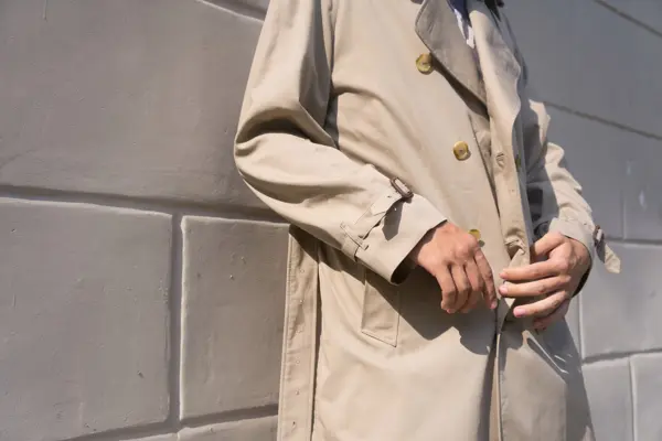 Nærbilde av en beige klassisk trenchcoat på en mann utendørs