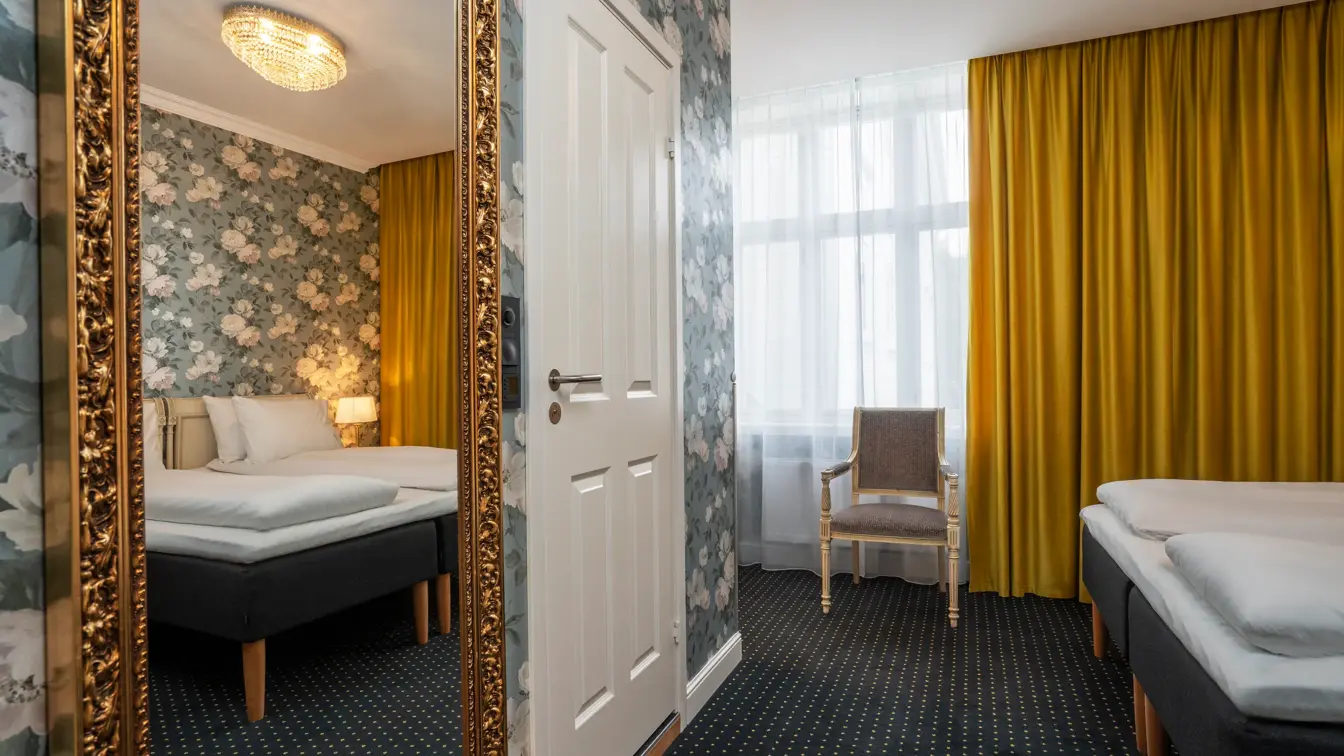 Veggspeil, gule gardiner, vindu, dobbeltseng, stol.