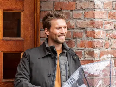 mann med dunvest, jakke og gjennomsiktig paraply