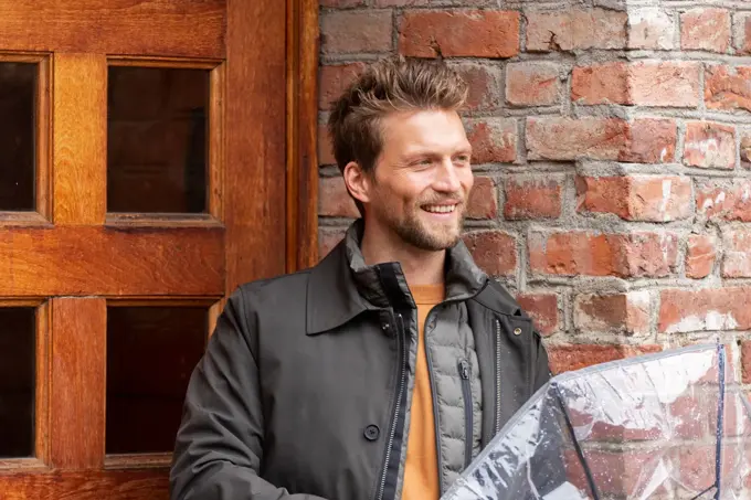 mann med dunvest, jakke og gjennomsiktig paraply