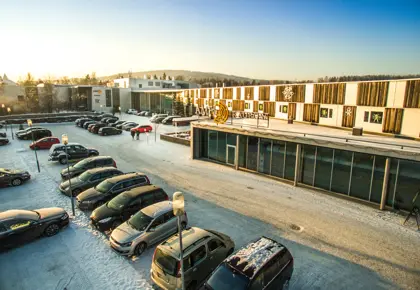 Fasadebilde av AMFI Raufoss viser biler parkert utenfor senteret om vinteren
