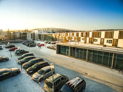 Fasadebilde av AMFI Raufoss viser biler parkert utenfor senteret om vinteren