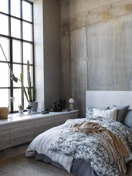 Seng med mønster sengesett, industrivindu og sementvegger