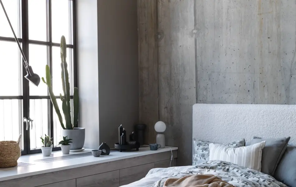 Seng med mønster sengesett, industrivindu og sementvegger