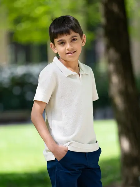 Gutt i hvit piquetskjorte og blå bukse