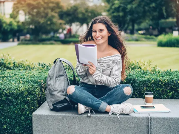 Student sitting outdoors and writing in a notebook