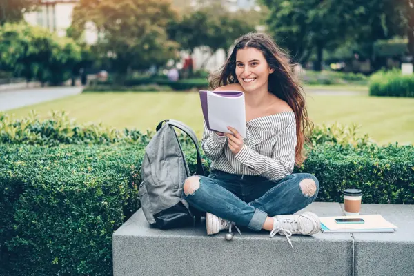 Student sitting outdoors and writing in a notebook