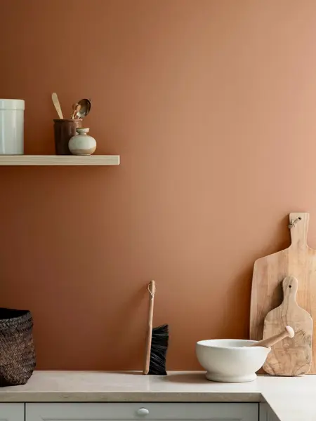 Kjøkkenbenk med trefjøler, hylle og en terrakotta vegg.