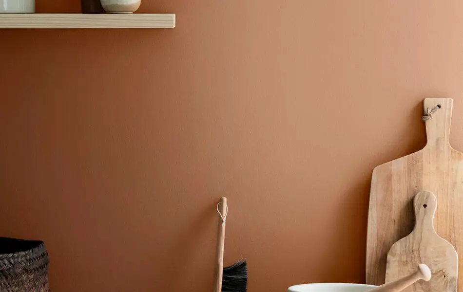 Kjøkkenbenk med trefjøler, hylle og en terrakotta vegg.