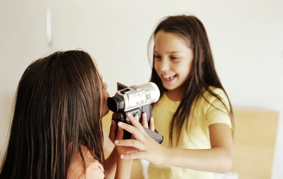 to jenter som holder et videokamera og filmer hverandre