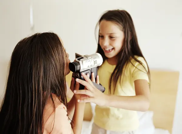to jenter som holder et videokamera og filmer hverandre