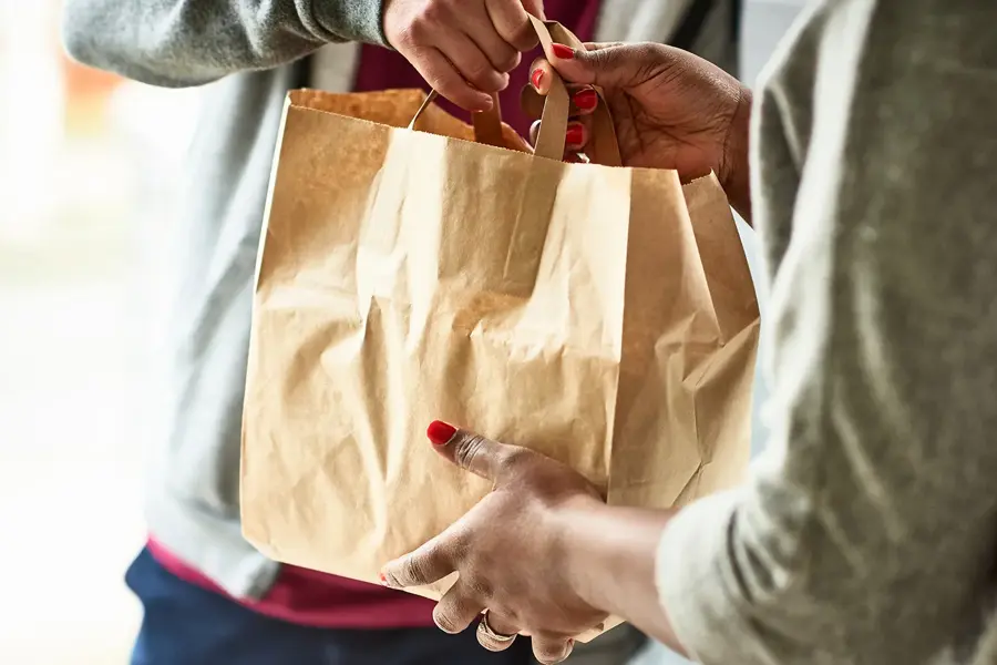 Person overleverer pappose med mat