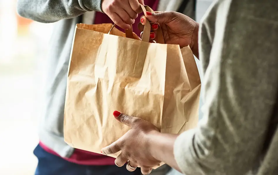 Person overleverer pappose med mat