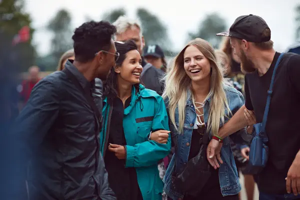Fire unge personer som står utendørs foran en større gruppe. Foto til artikkel om pakkeliste til festival.