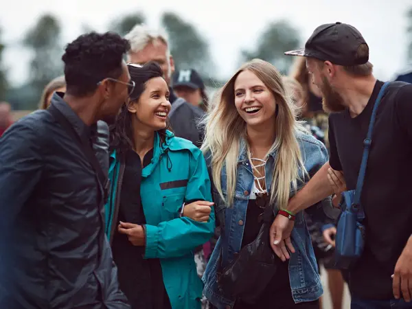 Fire unge personer som står utendørs foran en større gruppe. Foto til artikkel om pakkeliste til festival.