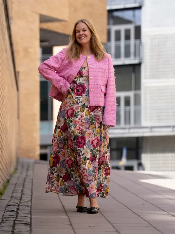 Dame med blomstrete lang kjole og rosa kort jakke