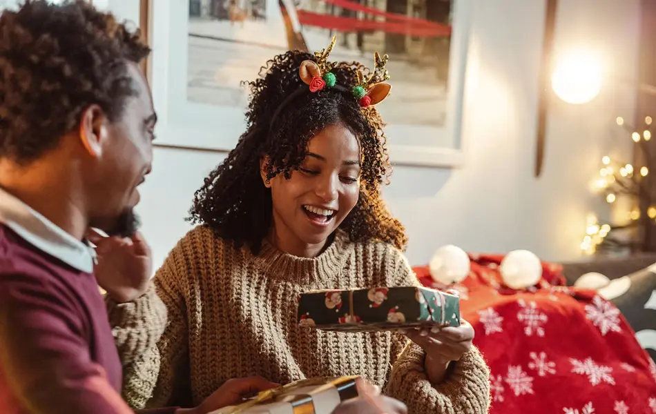 smilende dame som tar i mot julegave fra mannen sin