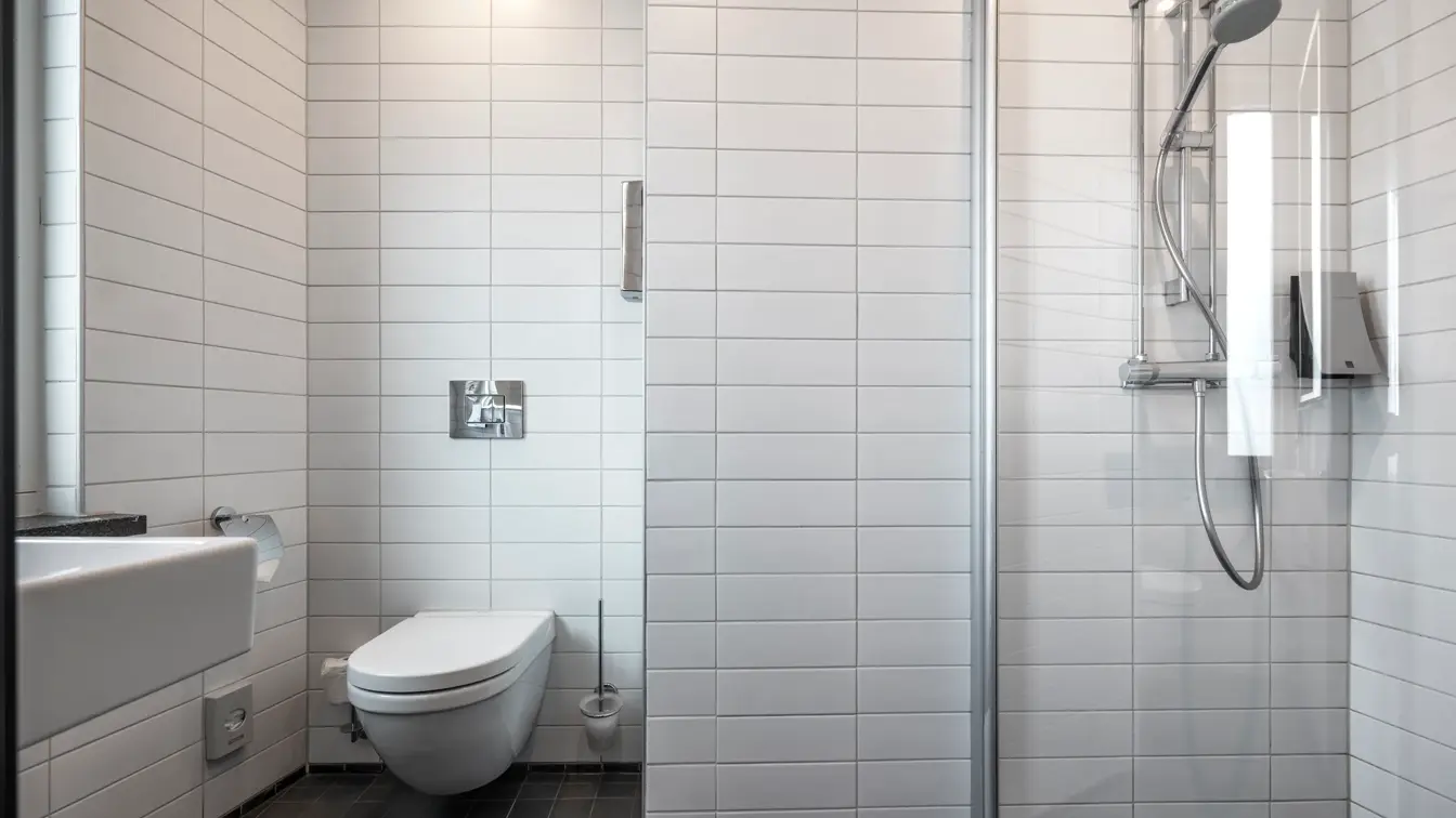 Bad med dusj og vegghengt toalett.