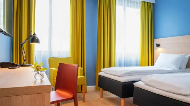 Separate senger, blå vegger, gule gardiner og skrivebord på standard rom twin på Thon Hotel Astoria
