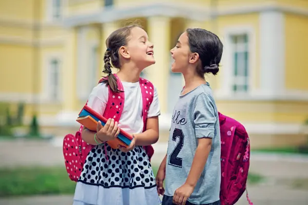 Two schoolgirls are making fun in the school yard at first day at school

