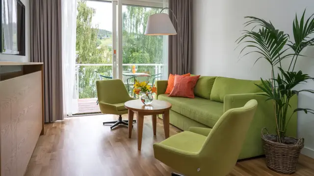 Blomster på bord i stua med sofa og to stoler på Thon Hotel Sandven i Nordheimsund
