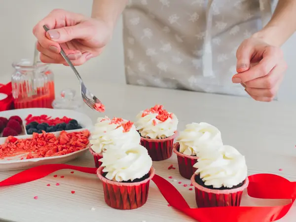Young girl prepares cupcakes. Decorating cupcakes for Valentine's day. The concept of home cooking. Selective focus. Toning.