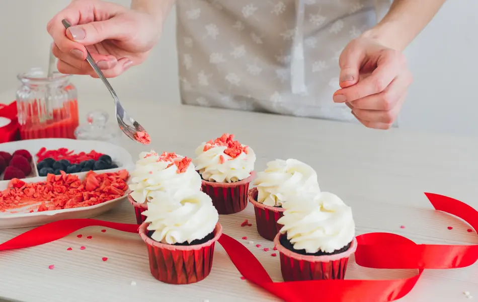 Young girl prepares cupcakes. Decorating cupcakes for Valentine's day. The concept of home cooking. Selective focus. Toning.