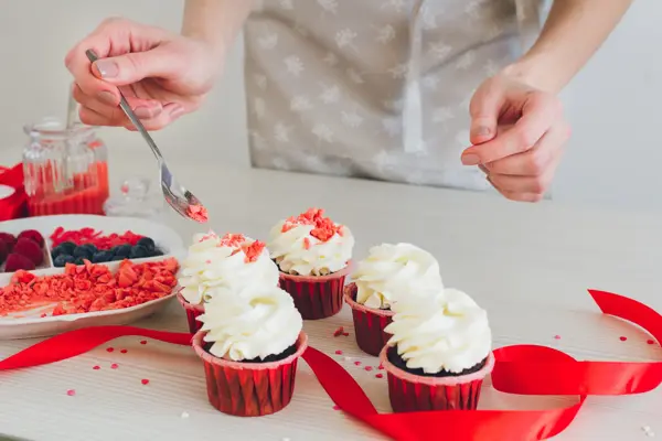 Young girl prepares cupcakes. Decorating cupcakes for Valentine's day. The concept of home cooking. Selective focus. Toning.