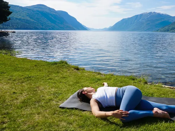 anny johansen viser yogaøvelser foran vakker fjord