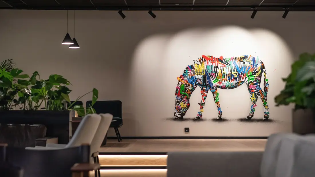 Fargerik sebra malt på hvit vegg i lobbyen på Thon Hotel Norge i Kristiansand.