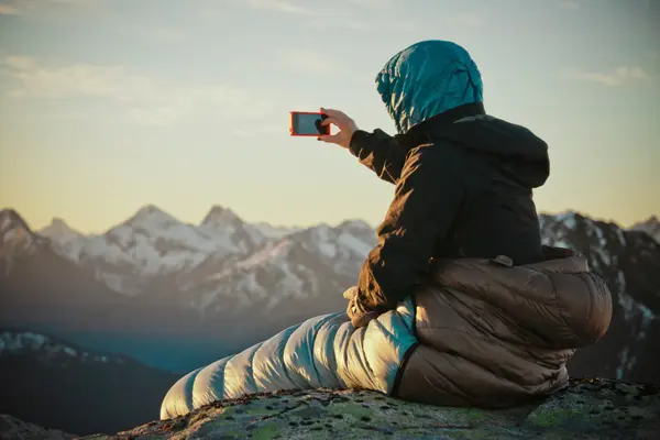 Backpacker takes a picture wil a camera phone.