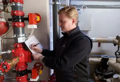 En mann skriver notater blant teknisk utstyr. 