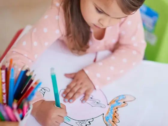 High angle shot of a little girl colouring in a picture at home
