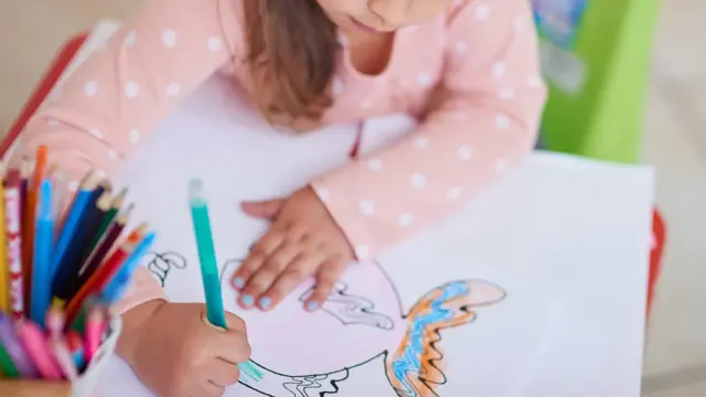High angle shot of a little girl colouring in a picture at home