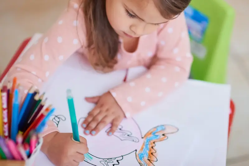 High angle shot of a little girl colouring in a picture at home
