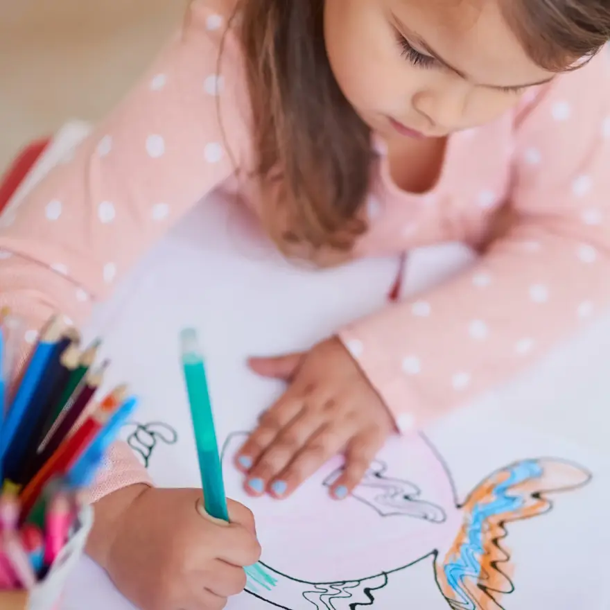 High angle shot of a little girl colouring in a picture at home