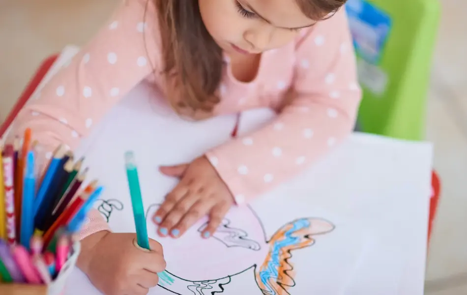 High angle shot of a little girl colouring in a picture at home