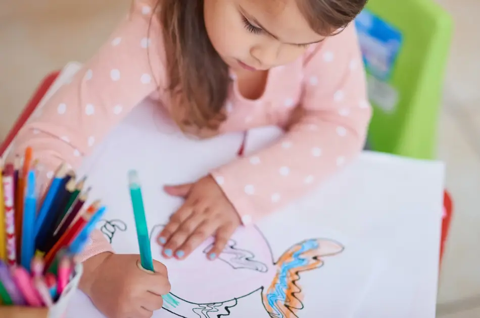 High angle shot of a little girl colouring in a picture at home