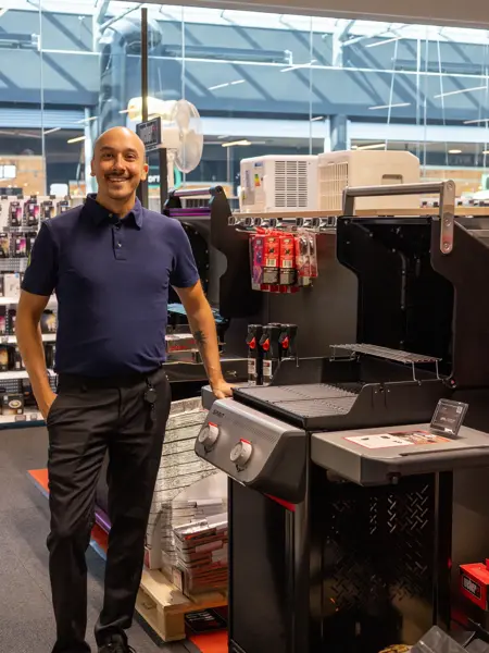 mann står ved grill i butikk
