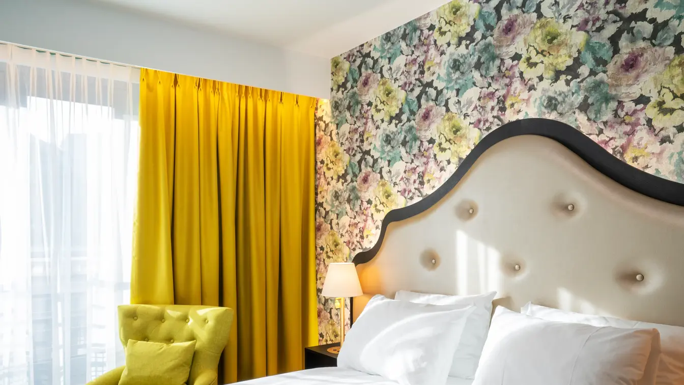 Blomstret tapet og dobbeltseng i dobbeltrom, gule gardiner på Thon Hotel Cecil i Oslo sentrum