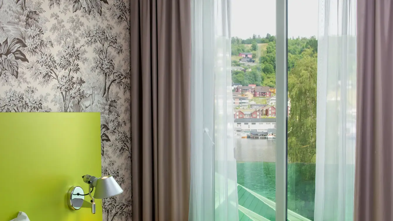 Seng med blomstertapet og utsikt ut vinduet på Thon Hotel Sandven i Nordheimsund